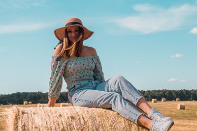 A beautiful young ukrainian woman sits on a hay bale and smiles