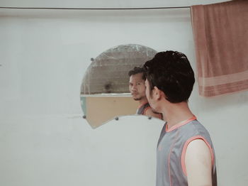 Portrait of young man looking in mirror