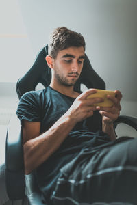 Young man using phone while sitting at home