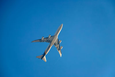 Low angle view of airplane flying against clear blue sky