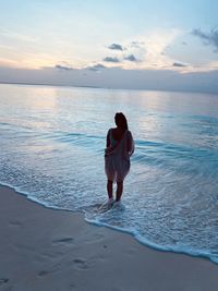 High angel view of woman standing at beach against sky