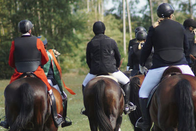 Rear view of people riding horses at fuchsjagd 