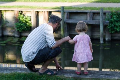 Rear view of father and daughter looking at pond