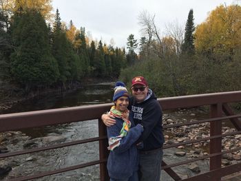 Portrait of friends standing by railing against trees