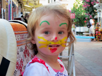 Portrait of cute girl with face paint standing on footpath in city