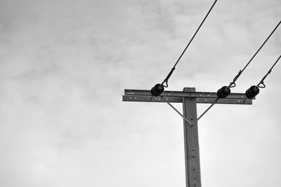 Low angle view of bird perching on cable against sky