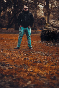 Full length of young man standing on field in forest