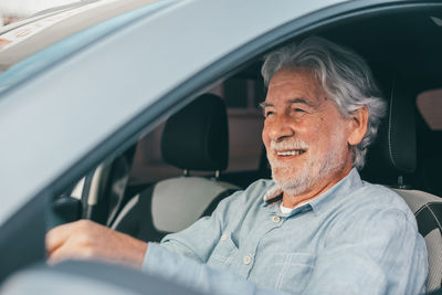 Smiling senior man sitting in car
