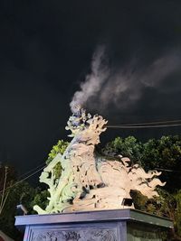 Low angle view of statue against building and sky