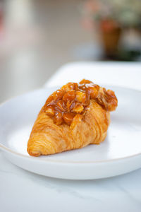 Croissant with macadamia nuts topping, homemade with white table background.