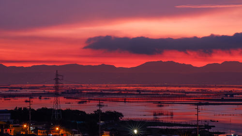 Silhouette city against orange sky during sunset