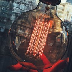 Close-up of red light bulb hanging on wood