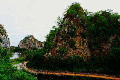 Scenic view of cliff by trees against sky