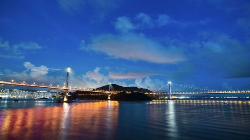 Illuminated bridge over river with city in background