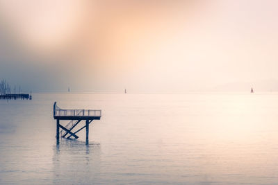 Lifeguard hut on pier at sea against sky