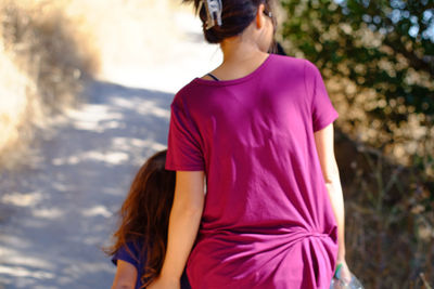 Rear view of mother and daughter walking on walkway