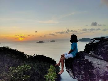 Man looking at sea against sky during sunset