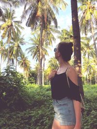 Young woman standing on palm trees