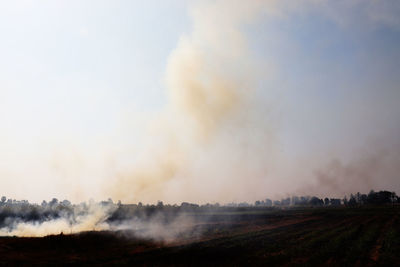 Smoke emitting from land against sky