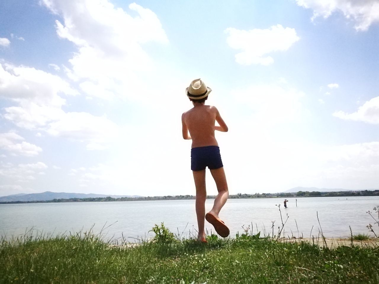 water, sky, hat, nature, cloud - sky, leisure activity, sea, real people, one person, full length, grass, beauty in nature, day, lifestyles, standing, rear view, scenics, outdoors, horizon over water, vacations, beach, young women, young adult