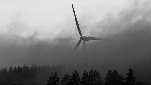 Low angle view of wind turbines against sky