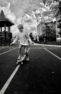 Boy standing on road against sky in city