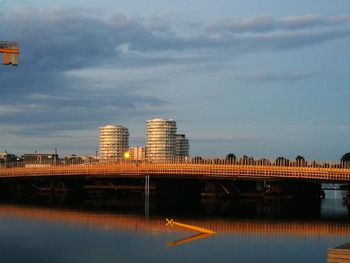 Bridge over river by buildings against sky in city