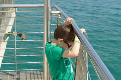 Boy standing by railing on boat