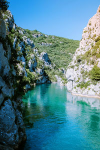 Scenic view of river and mountains against clear blue sky