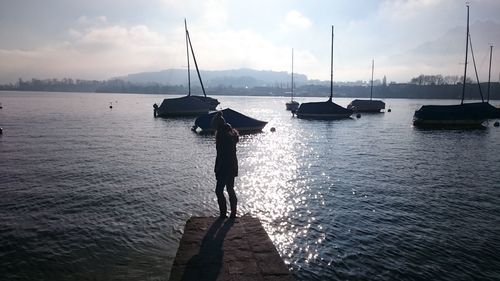 Silhouette of man fishing in sea against sky