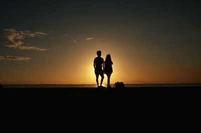 Silhouette of people on beach at sunset