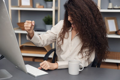 Young woman using mobile phone while sitting on table