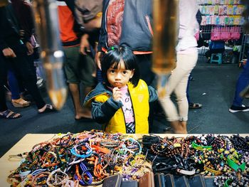 Portrait of cute girl standing by bracelet stall at street market