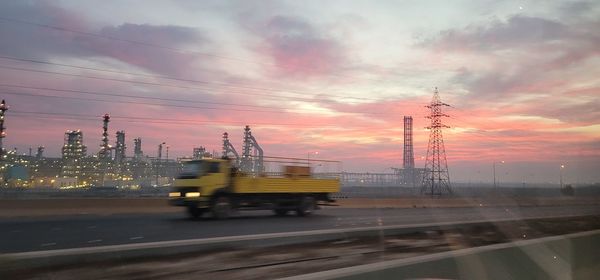 Cars on road against sky during sunset