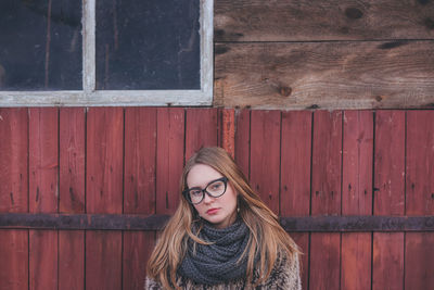 Portrait of young woman standing against wall