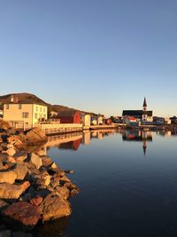 Buildings by sea against clear sky