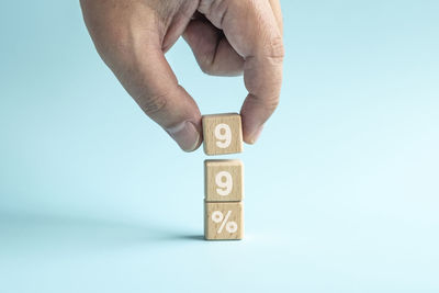 Cropped hand holding toy blocks against blue background
