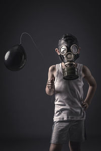 Child with gas mask and black balloon, studio shot