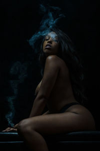 Midsection of woman sitting against black background