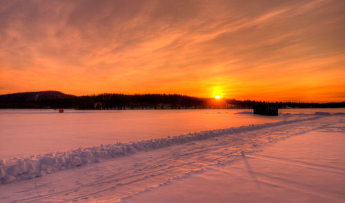Scenic view of frozen lake against orange sky during sunset