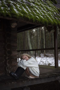 Portrait of young woman sitting on retaining wall