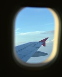 Close-up of airplane wing against sky seen through window
