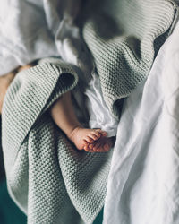 Low section of baby relaxing on bed at home