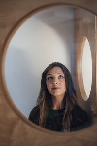 Young woman looking up seen through glass