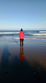 Rear view of man on beach against sky