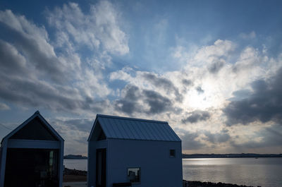 Buildings by sea against sky