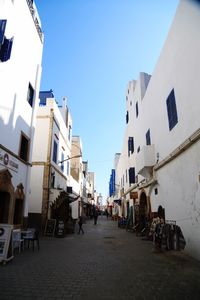 Street amidst buildings against clear blue sky