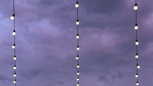 Low angle view of illuminated street lights against sky