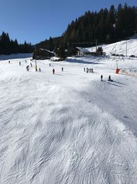 People on snow covered landscape against blue sky