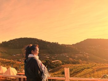 Woman standing on mountain against sky during sunset